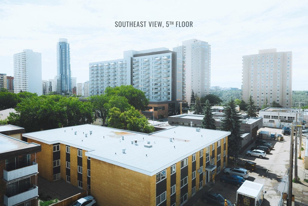 a view of a building with a white roof with tall buildings