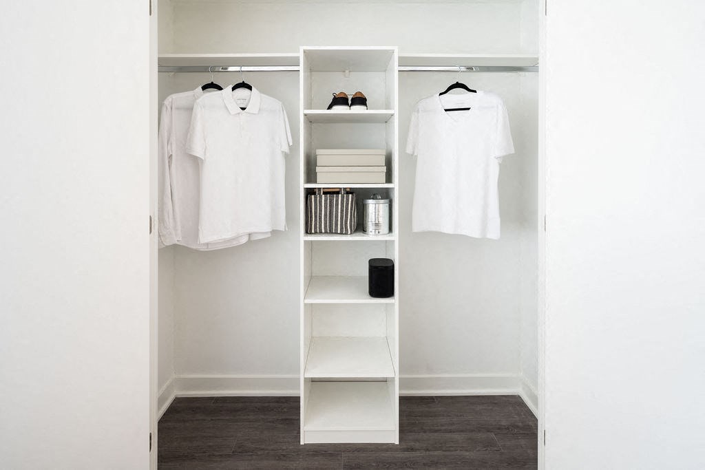 a walk in closet with a white closet organizer