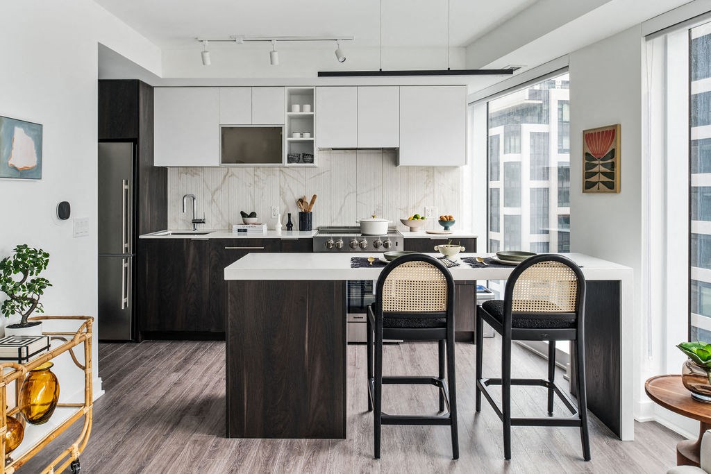 a kitchen with white cabinets and a white counter top with black chairs