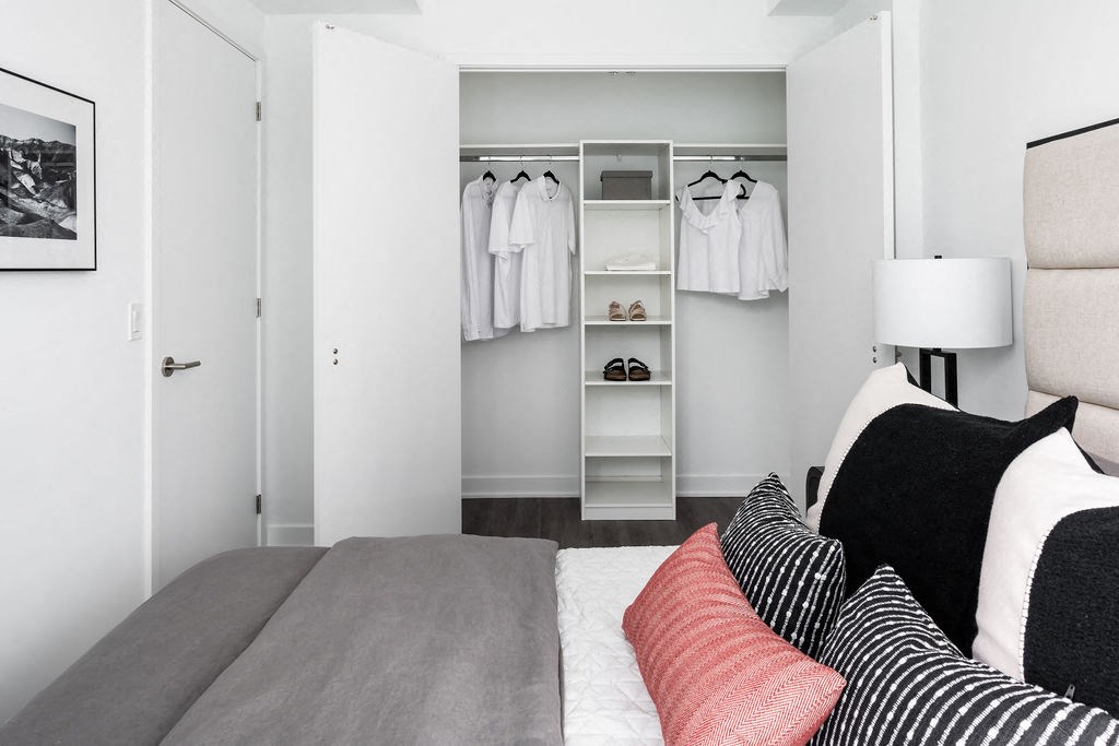 a bedroom with a bed with pillows and a closet with clothes