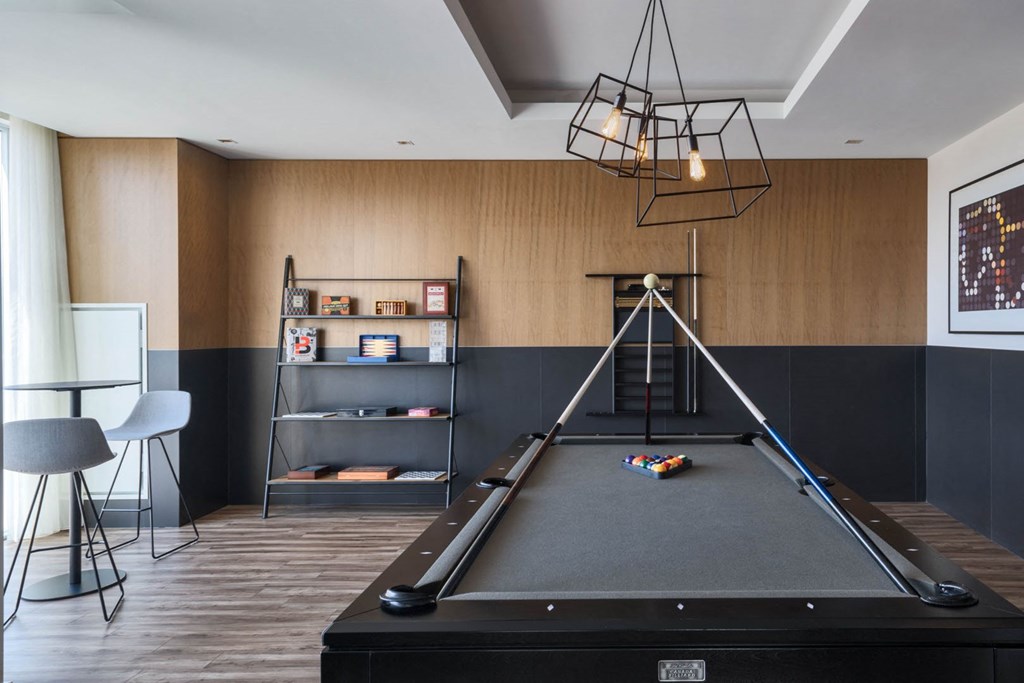 a games room with a pool table and a modern light fixture
