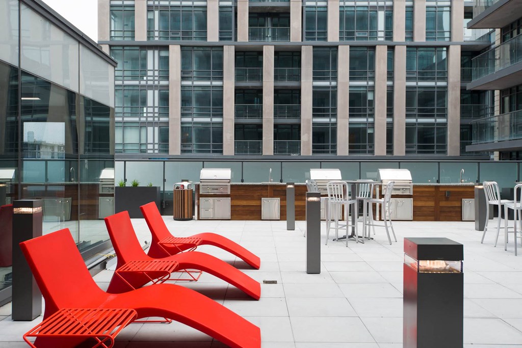 an outdoor patio with red chairs and tables in front of an office building