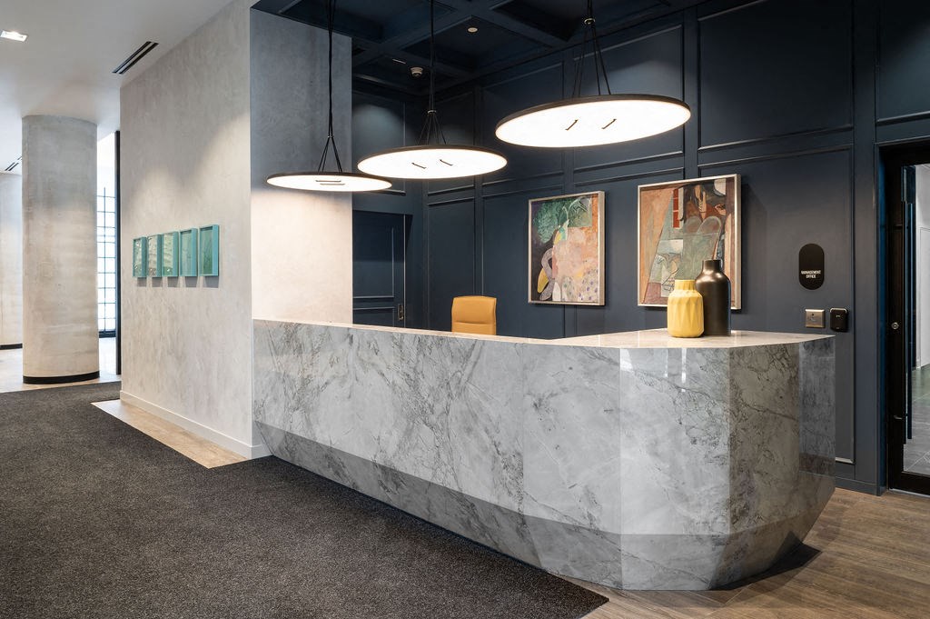 a marble reception desk in a room with blue walls and lamps