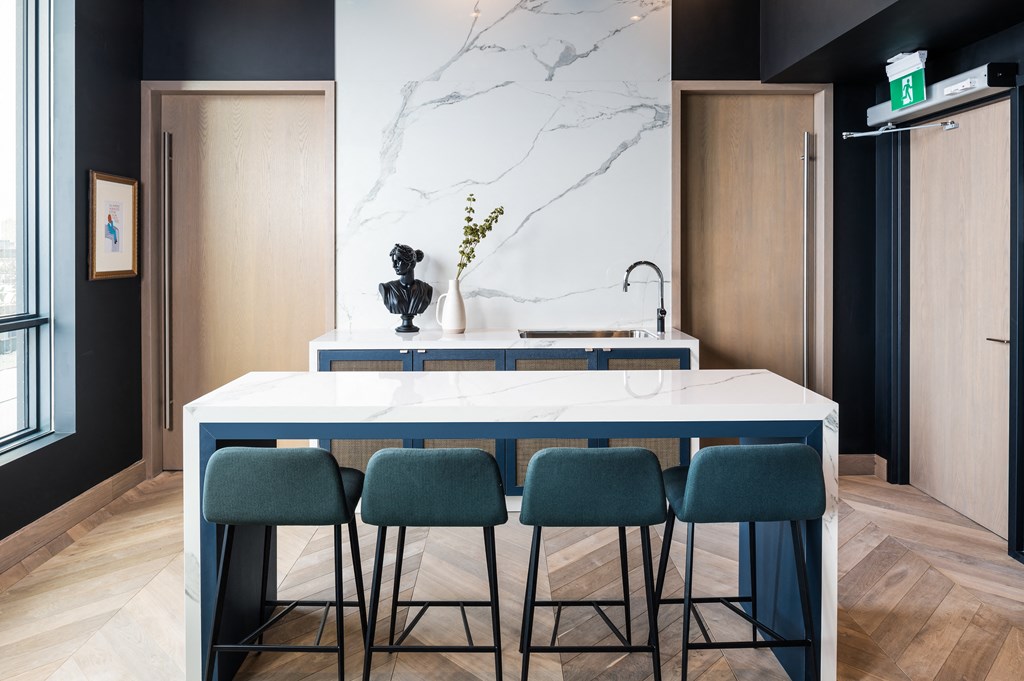 a kitchen with a marble counter top and blue chairs