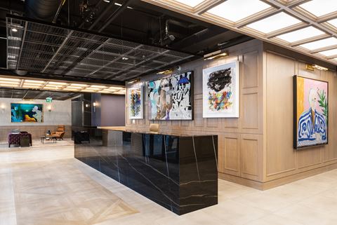 the lobby of a hotel with a reception desk and paintings on the wall
