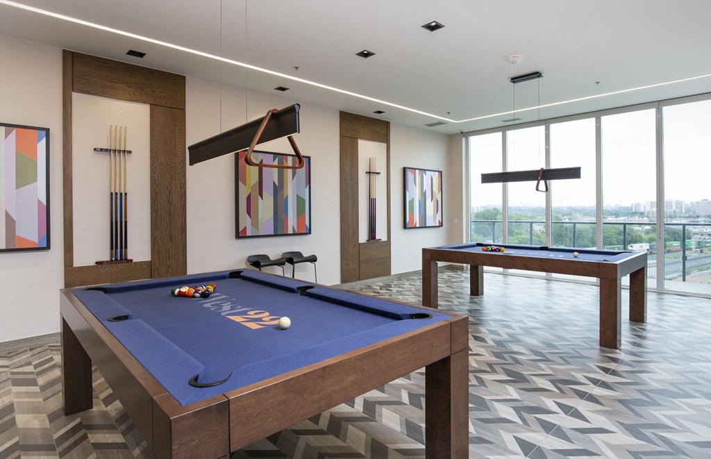 a games room with two pool tables and views of a city