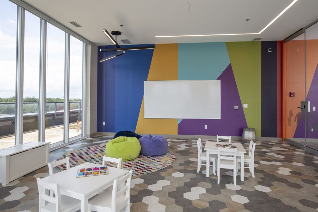 a living room with tables and chairs and a wall with a painting on it
