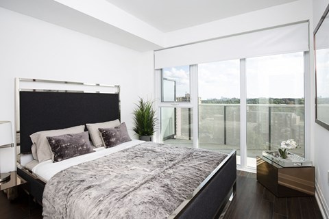 A bedroom with a large bed and a view of the outside through the window.
