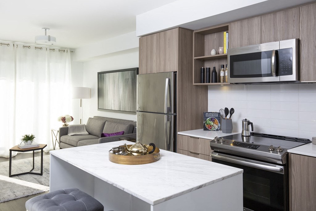 a kitchen and living room with a white counter and a refrigerator