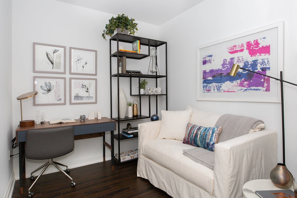 a small living room with a white couch and a desk