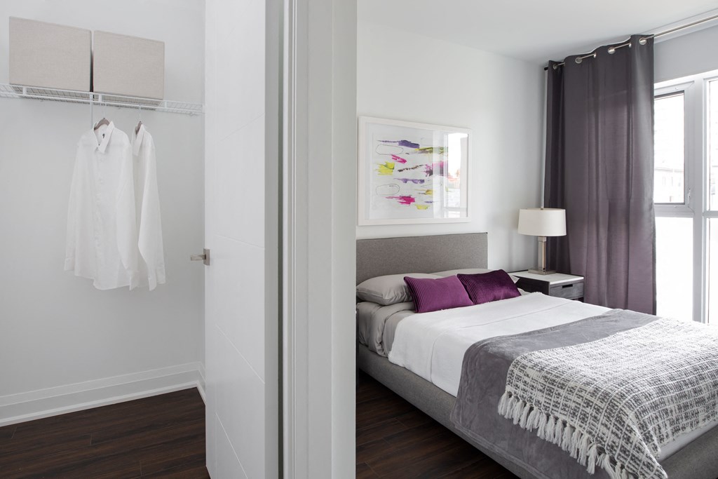 a bedroom with white walls and a bed with purple pillows