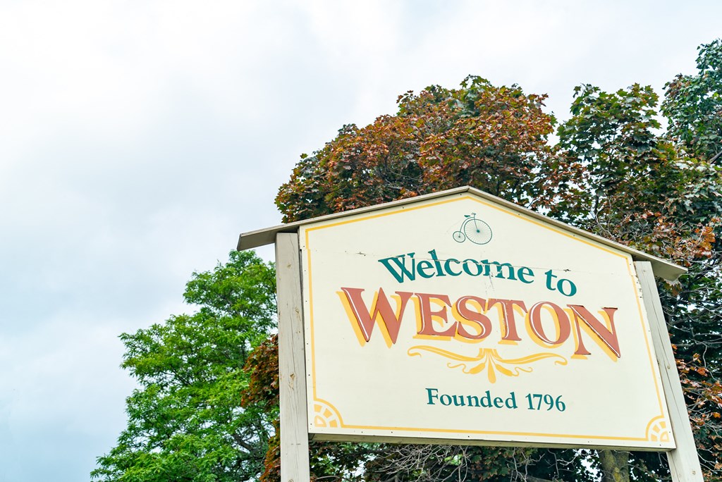 a welcome to weston sign in front of trees