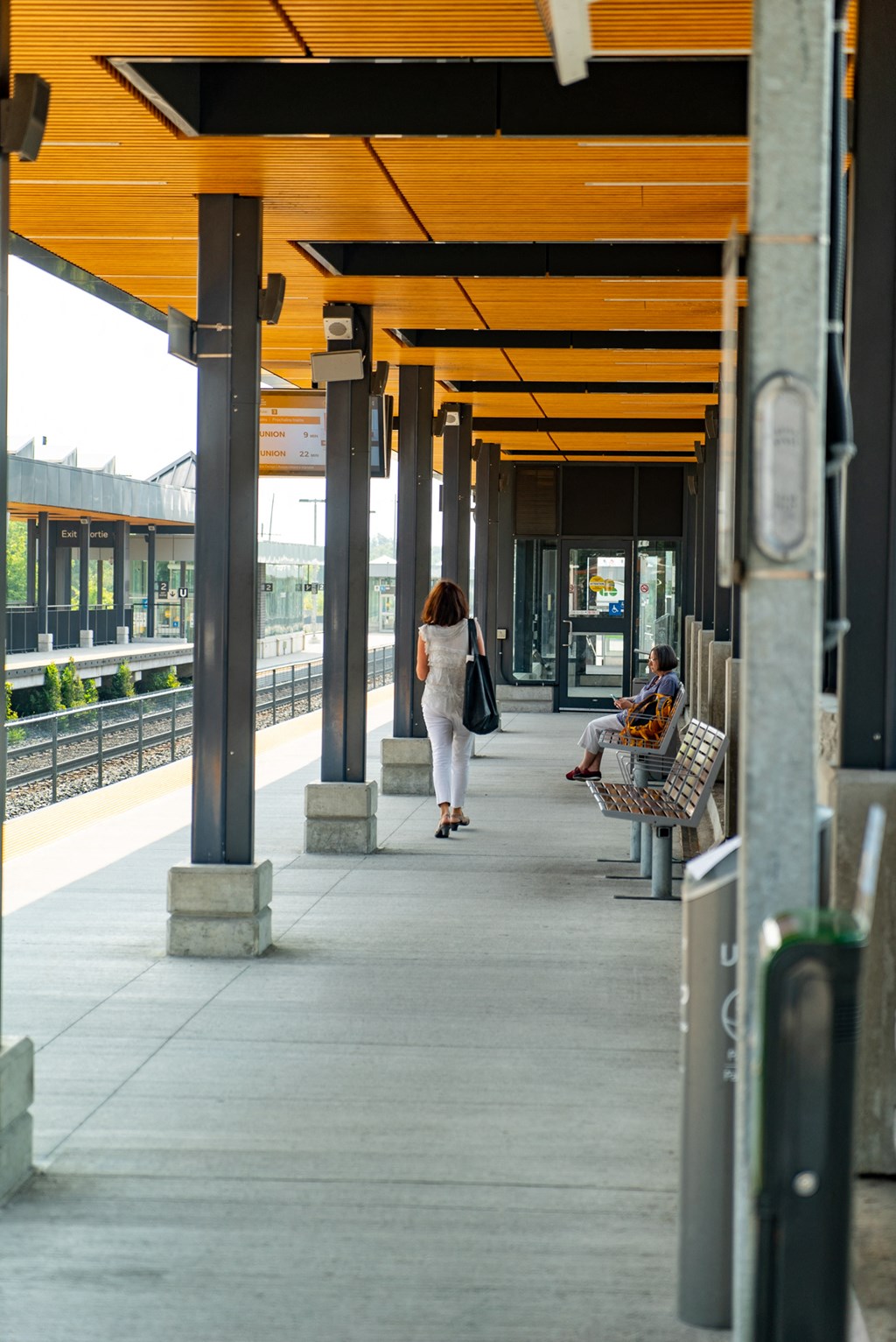 a woman walking down a covered walkway at a train station