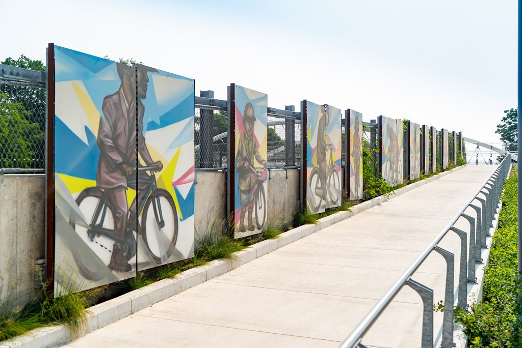 a row of murals on a fence next to a sidewalk