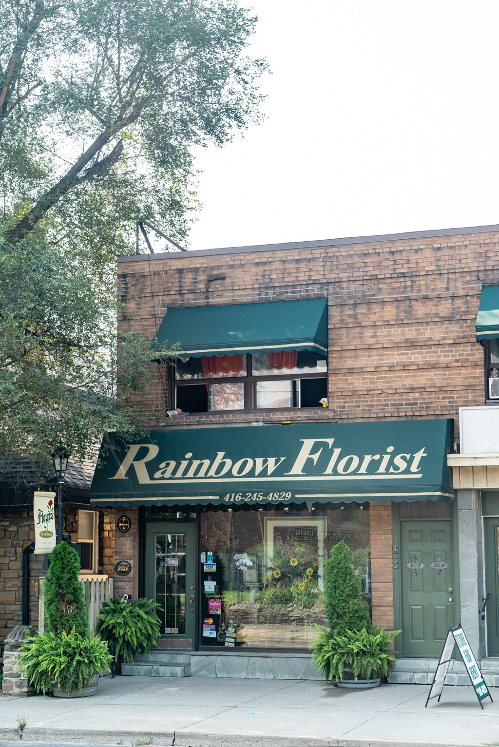 the front of a brick building with a green sign that reads rainbows floret