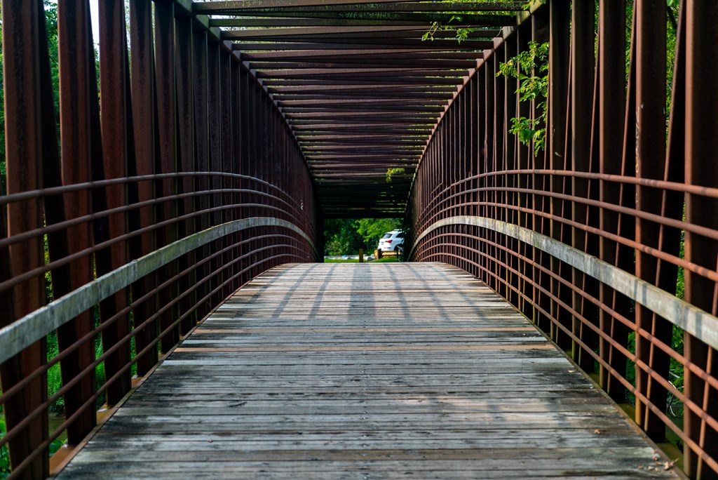 the end of a bridge with a wooden deck and red rails