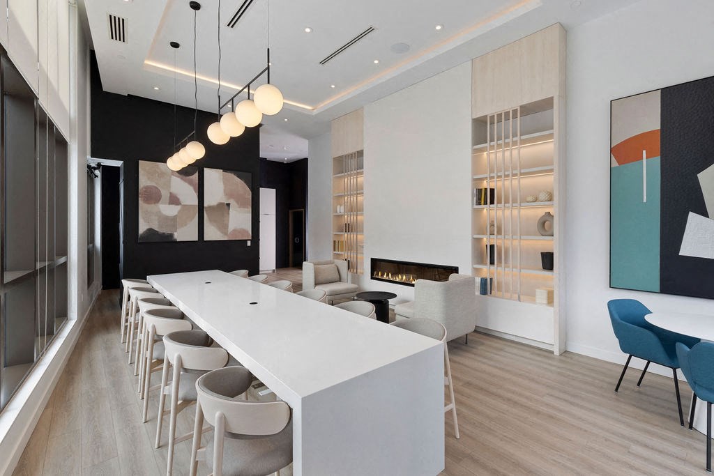 A long white table with chairs on either side is in the middle of a room.