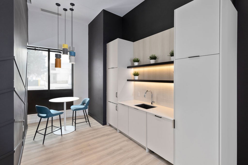 A modern kitchen with white cabinets and a black wall.