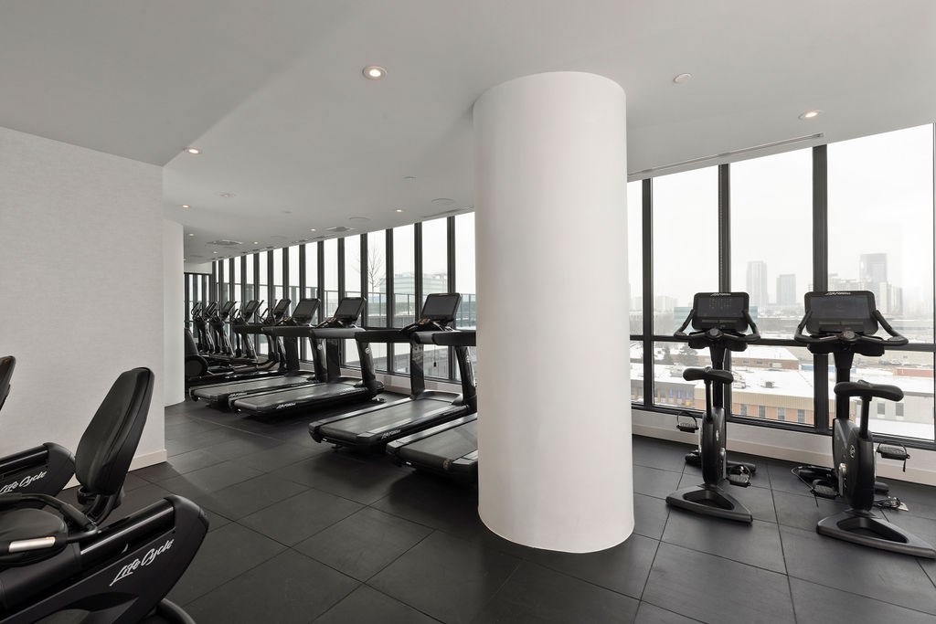 A gym with treadmills, exercise bikes and a large window.