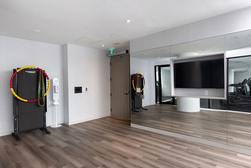 A room with a wooden floor and a black TV on a white stand.