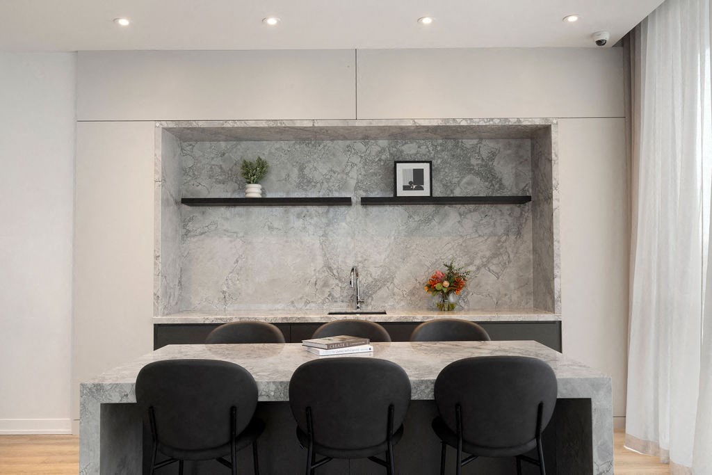 A modern kitchen with a marble backsplash and grey countertop.