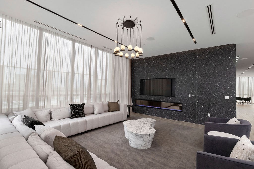 A modern living room with a white sofa, a grey coffee table, and a black and white speckled wall.