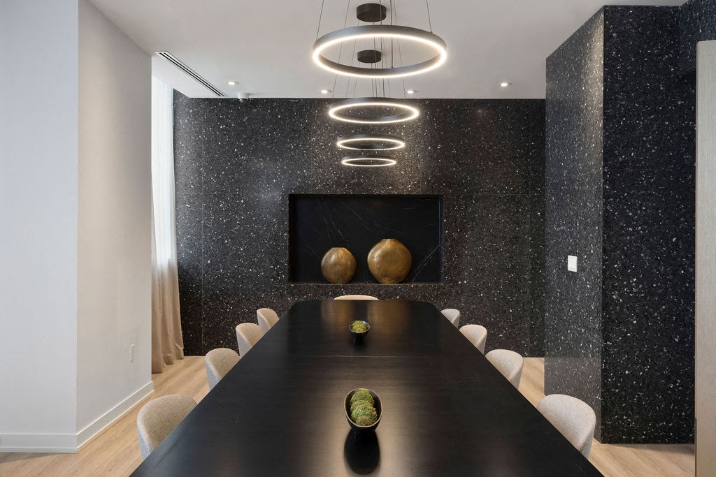 A long black table with a bowl of fruit on it and a black wall with a gold sphere and a black and white speckled design.