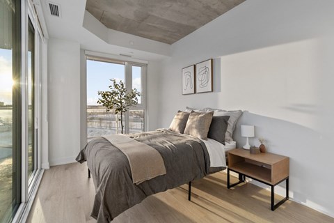A bedroom with a large bed and a small table by the window.