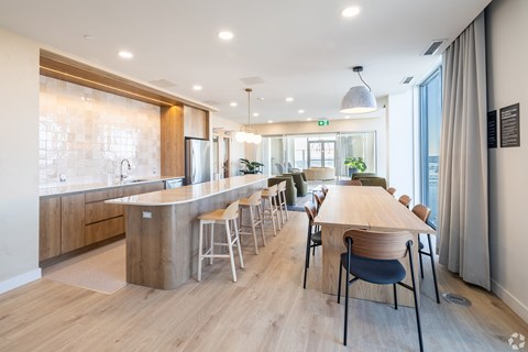 A modern kitchen with a long wooden table and chairs.