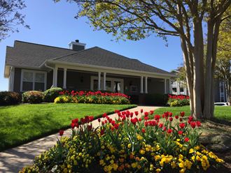 the front of a house with tulips in the front yard