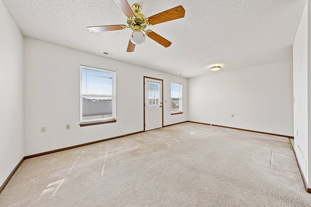 the living room and dining room of an empty house with a ceiling fan