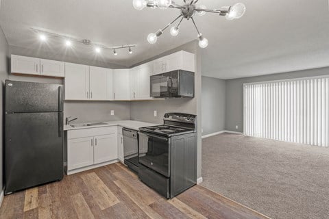 an empty kitchen with white cabinets and a black stove and refrigerator