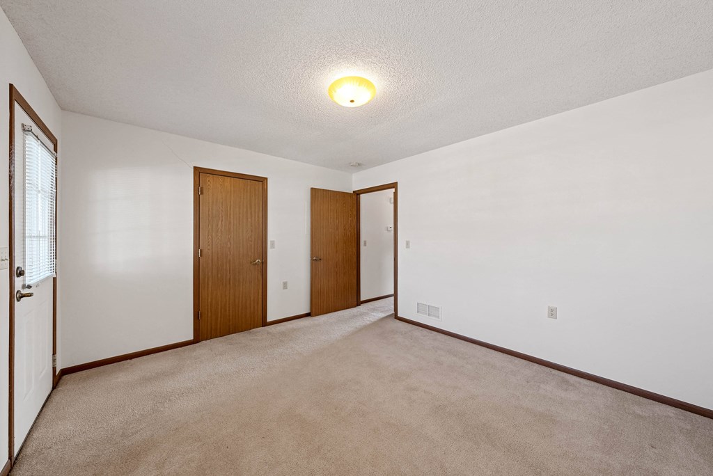 the living room is empty and has a door to the hallway
