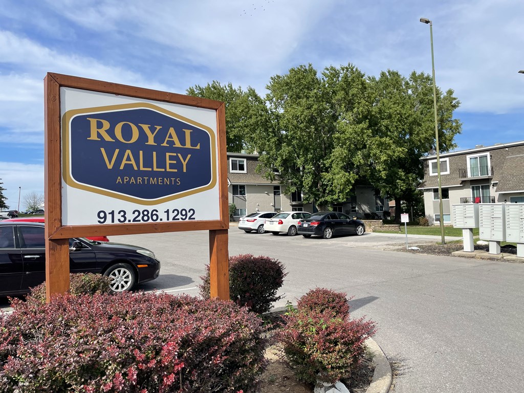 a sign for royal valley apartments in front of a parking lot