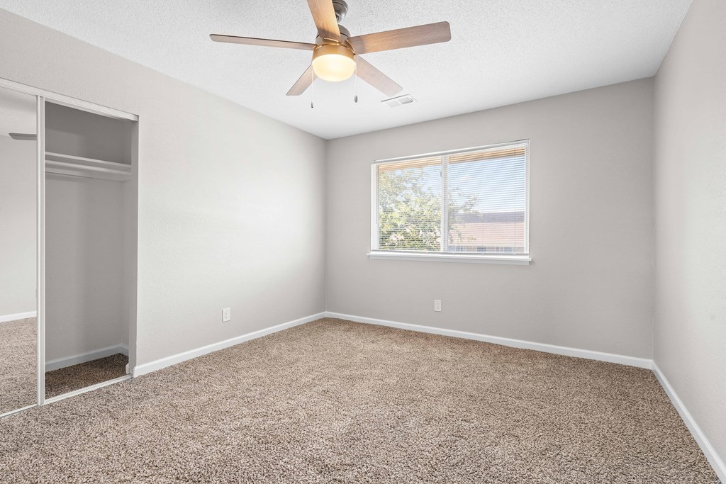 an empty room with a ceiling fan and a window