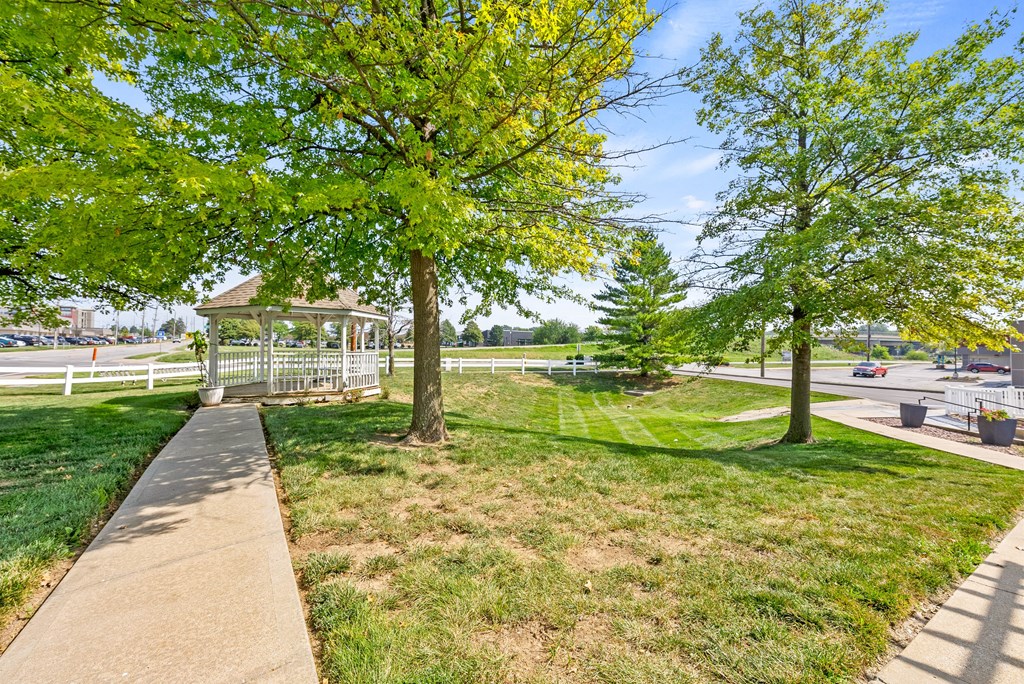a park with trees and a gazebo on the grass