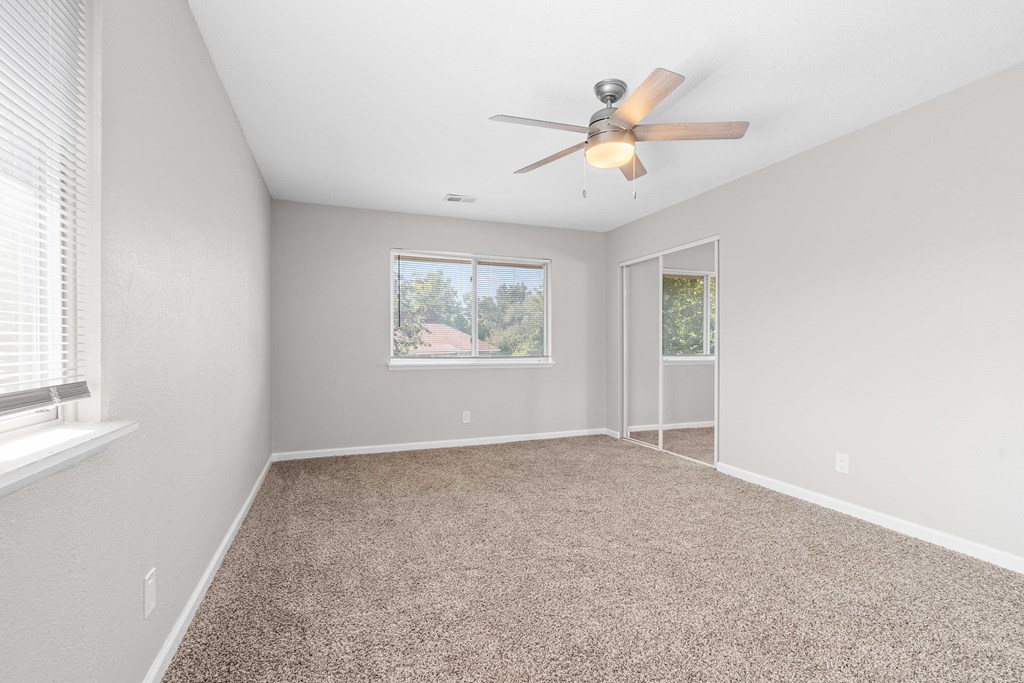 an empty living room with a ceiling fan and a window