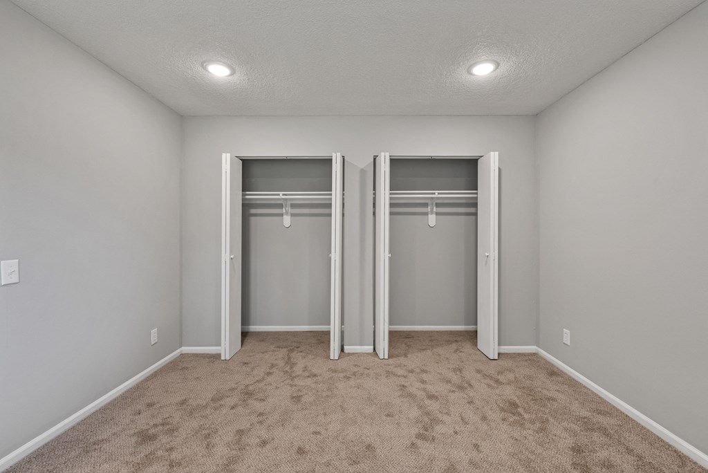 an empty bedroom with two closets and a carpeted floor
