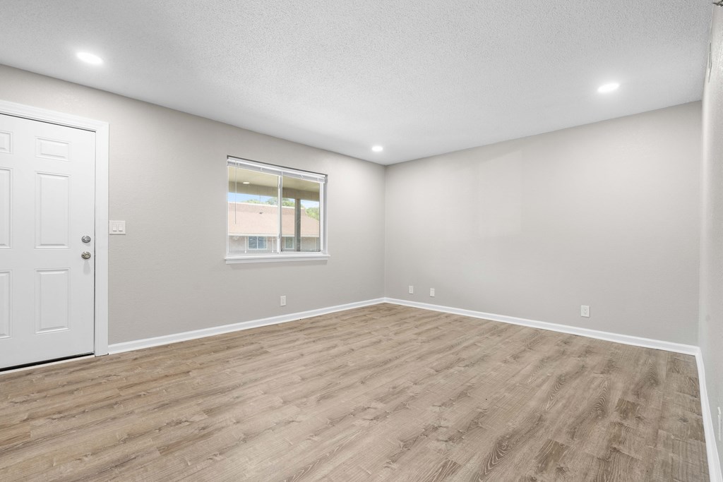 an empty living room with wood flooring and a window