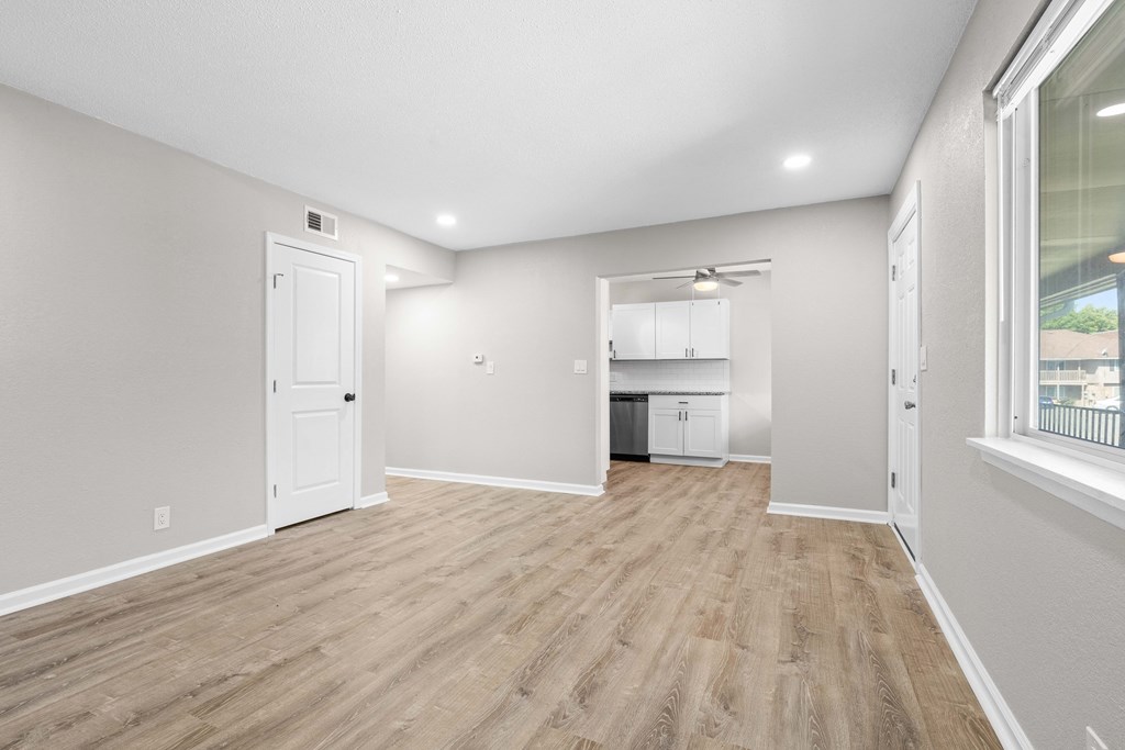 the living room and kitchen of a new home with white walls and wood flooring