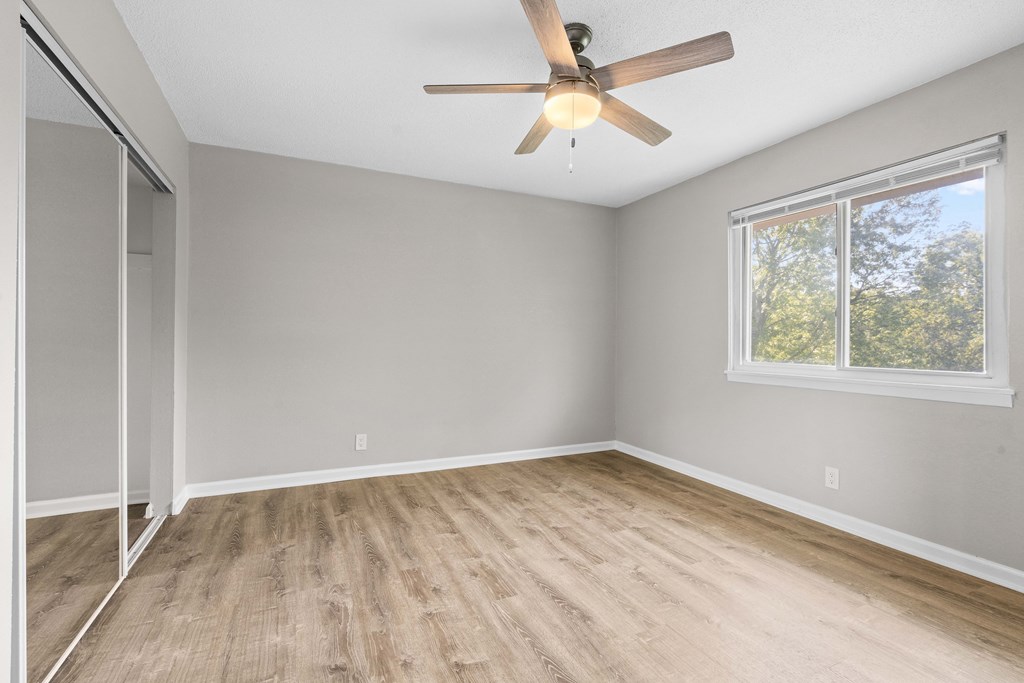 an empty room with a ceiling fan and a window