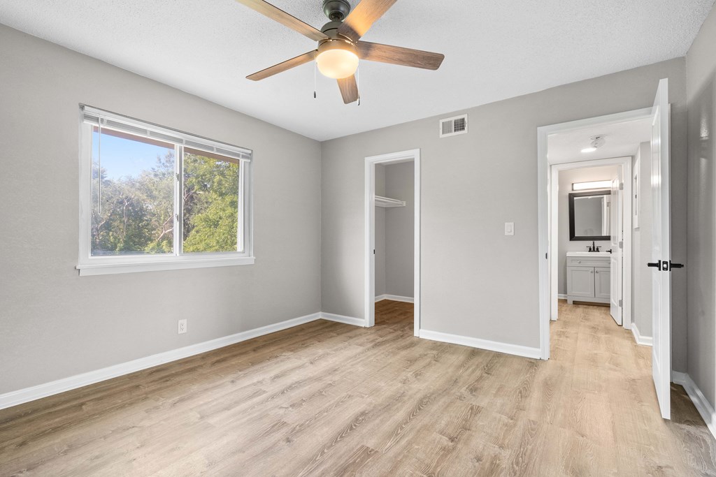 an empty room with a ceiling fan and a door to a bathroom