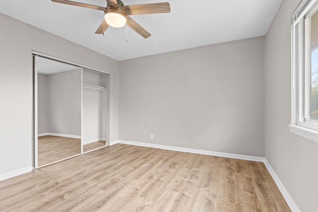 an empty room with a ceiling fan and a mirror