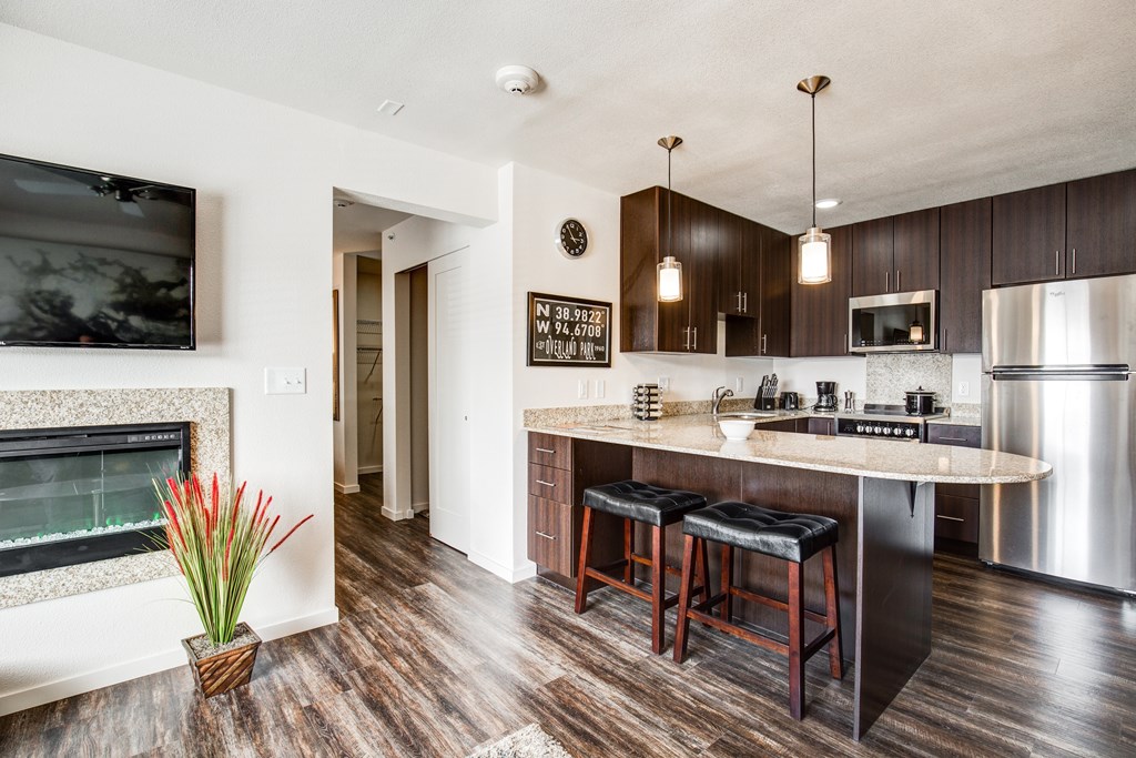 A modern kitchen with dark wood floors and stainless steel appliances.