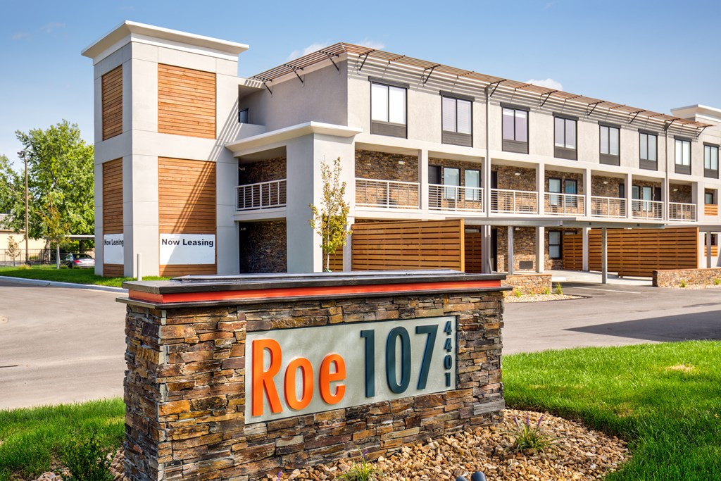 A multi-story building with a sign that reads "Roe 107" in front of it.
