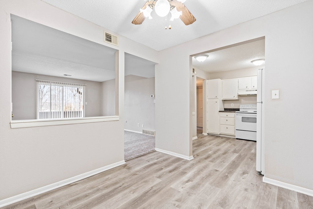 a spacious living room with a kitchen in the background
