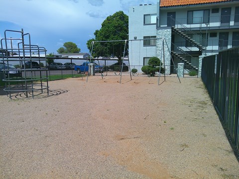 A playground with a swing set and a slide in front of a white building.