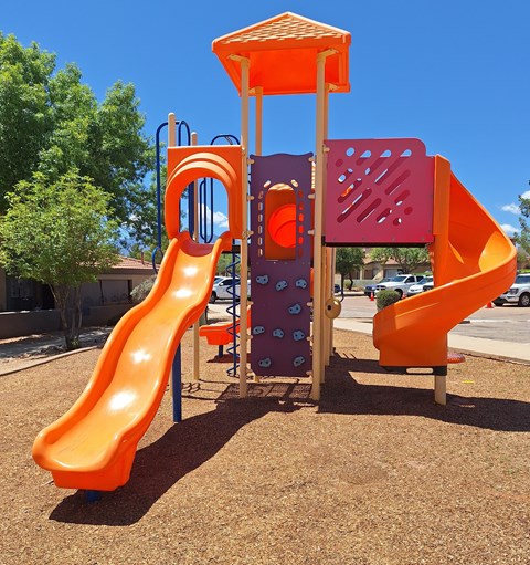 A playground with a yellow slide and a purple and orange structure.