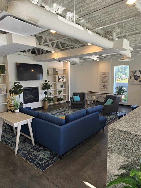 A living room with a blue couch and a television on the wall.