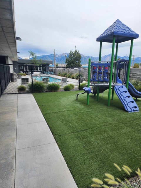 A playground with a blue slide and a green swing set.